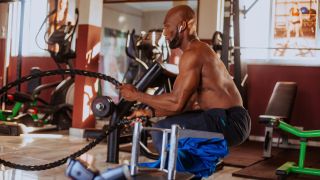 Man working out doing battle rope waves wearing headphones