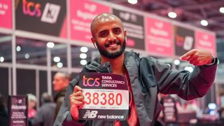 Man points at his London Marathon bib number standing in front of a row of booths at the London Marathon Running Show