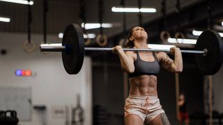 A woman completing a CrossFit workout with a barbell 