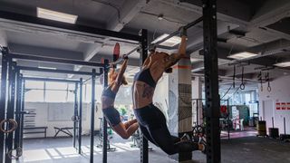 Two women performing kipping pull-ups in a gym